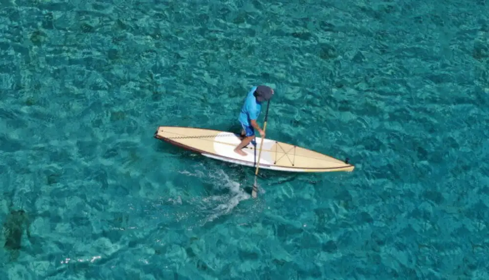 Aerial drone ultra wide photo of fit unidentified man practising in SUP board or Stand UP Paddle surf board in tropical exotic island turquoise sea